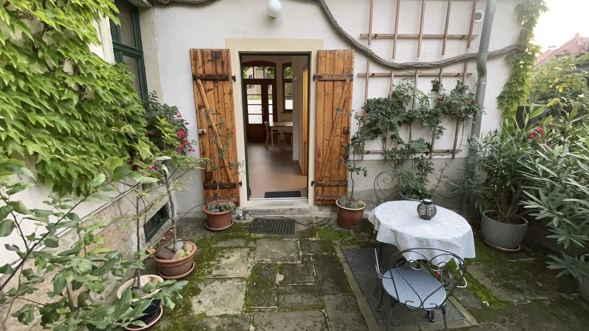 Sitzplatz im Hof mit Tisch, Gartentür und Pflanzen