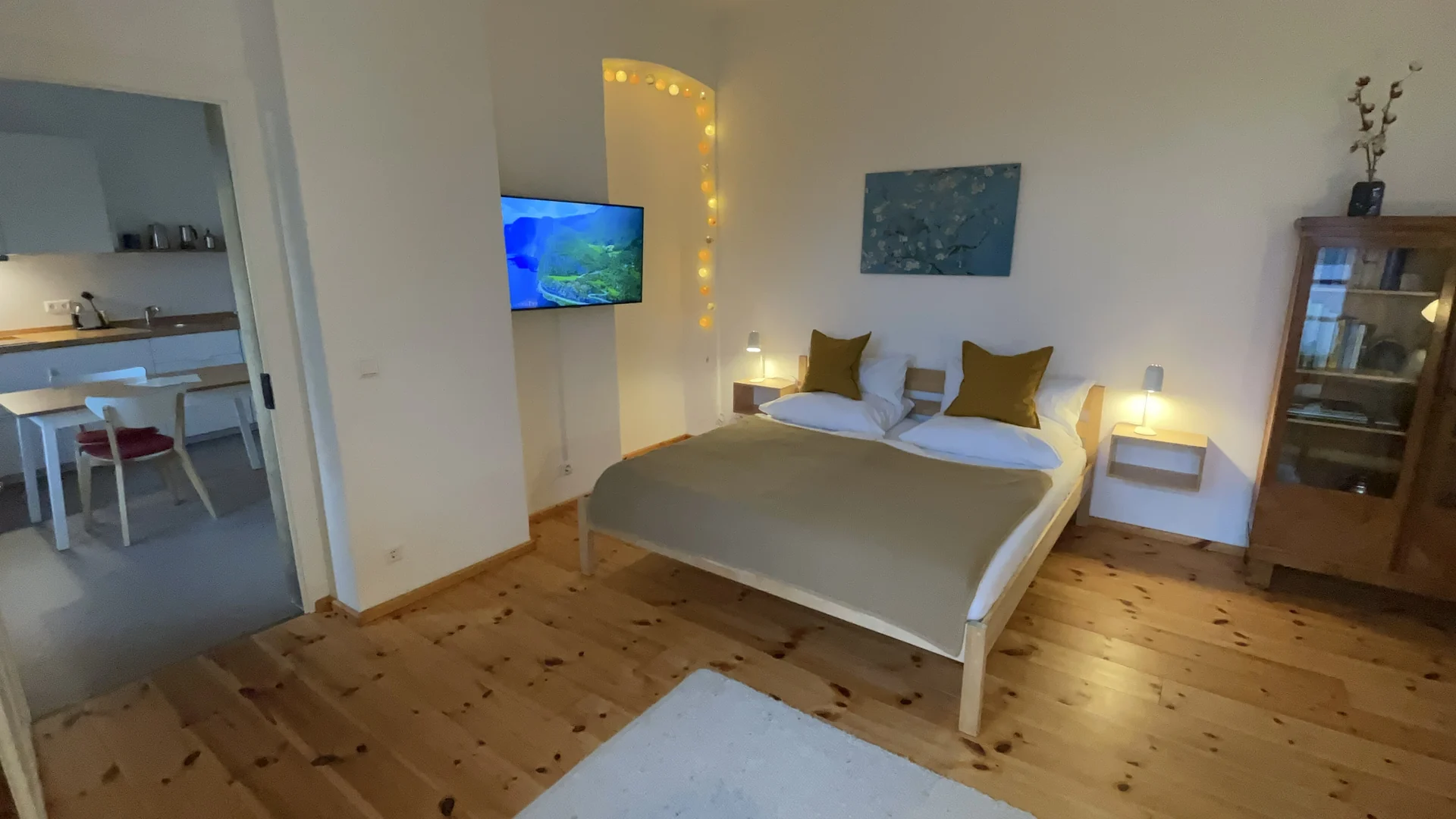 Schlafbereich mit Queensize-Bett, Fernseher und Blick in die Küche