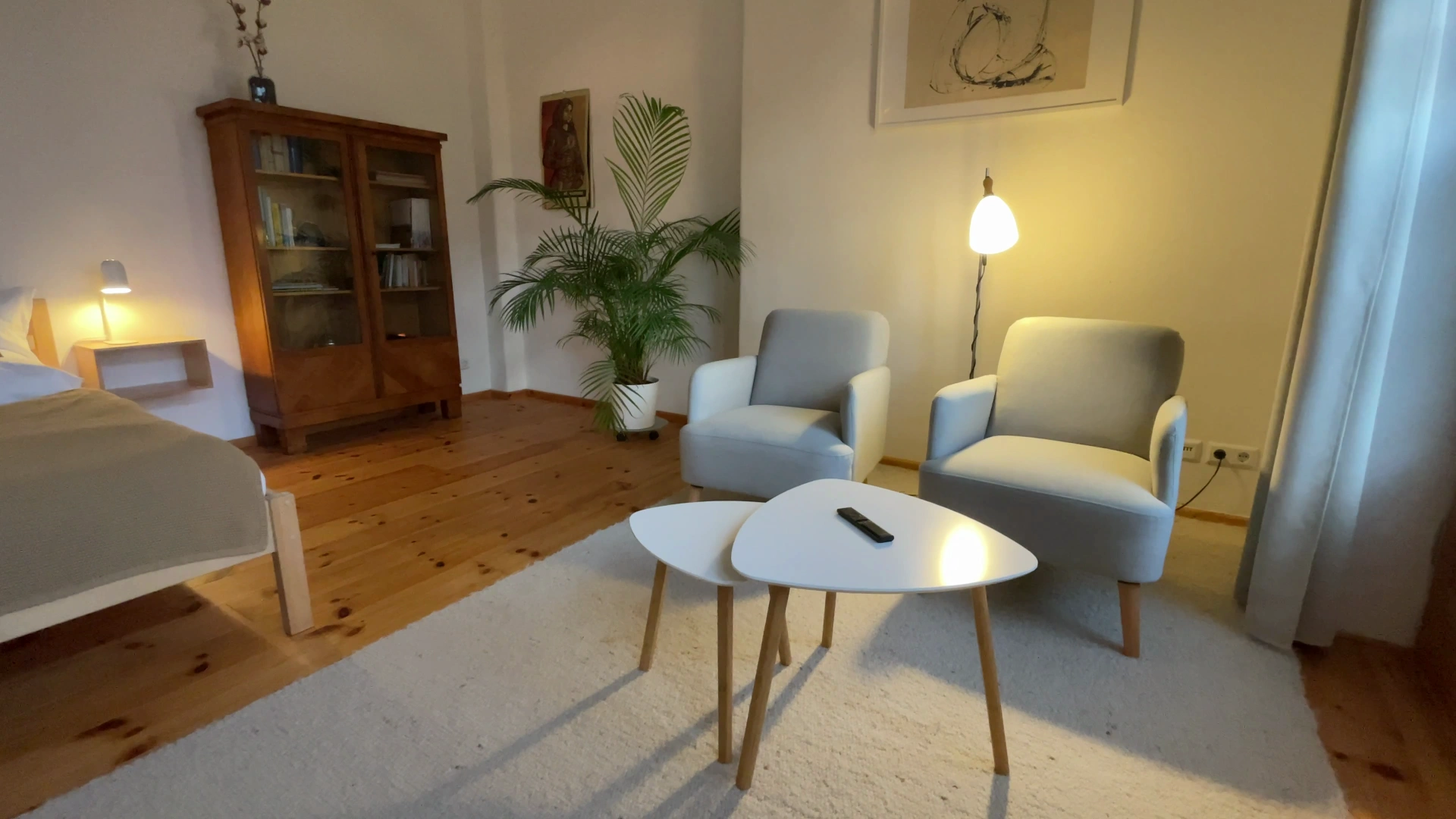 Sitzecke mit zwei Sesseln, Beistelltischen, Stehlampe, Bücherschrank und Palme